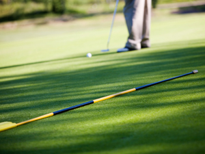 Close-up of man putting golf ball in to hole